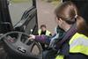 A woman driver behind at the wheel of a truck, being instructed.