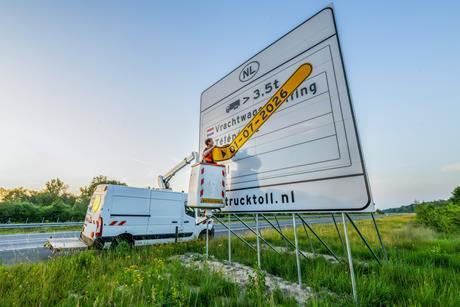 Worker removes date strip from truck toll sign