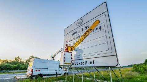 Worker removes date strip from truck toll sign